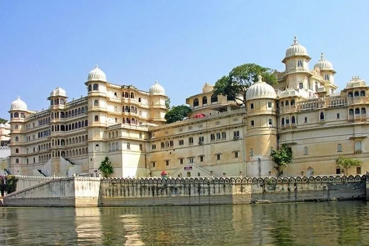 A large, multi-tiered palace complex situated alongside a serene lake.