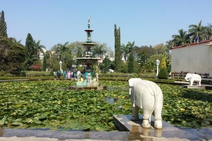 Ein Gartenbrunnen, umgeben von einem Seerosenteich und Elefantenstatuen.